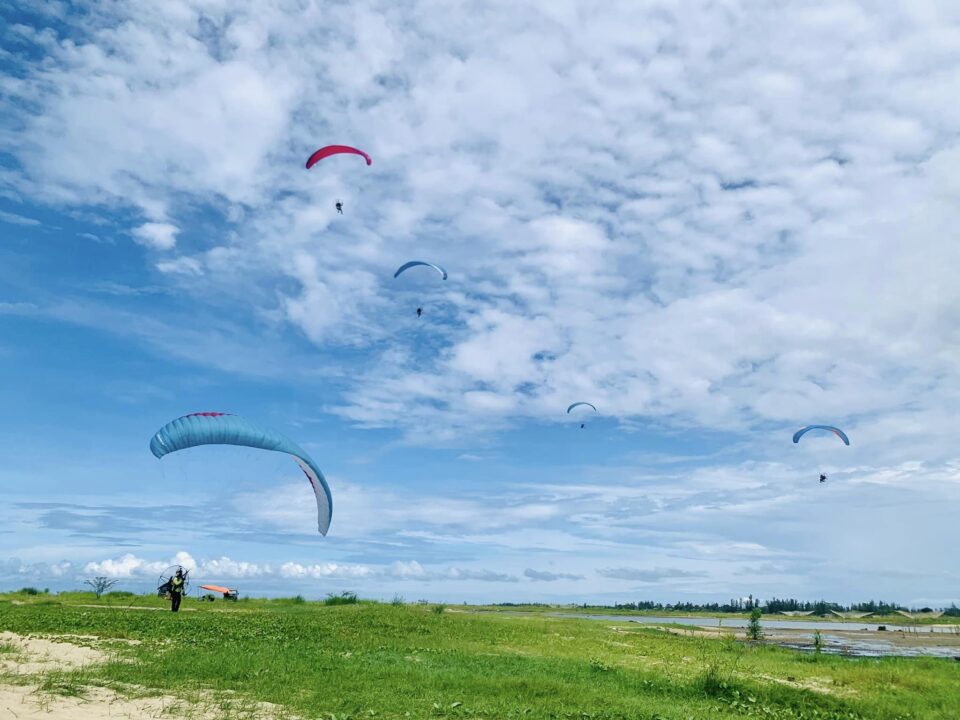 Tandem paragliding over green rice field in Hoi An with blue sky